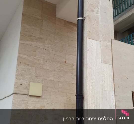 צינור ניקוז שחור מחובר לקיר חיצוני